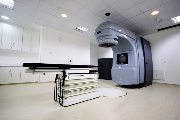 Aparelho de radioterapia. Consiste de uma mesa de exames e o aparelho que remete a um poste de luz