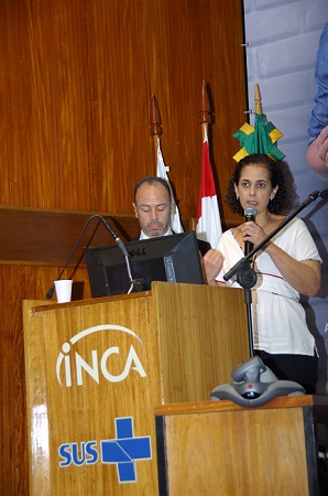 Os pesquisadores André Pichon e Marcia Pinto em cima do palco, atrás de um púlpito