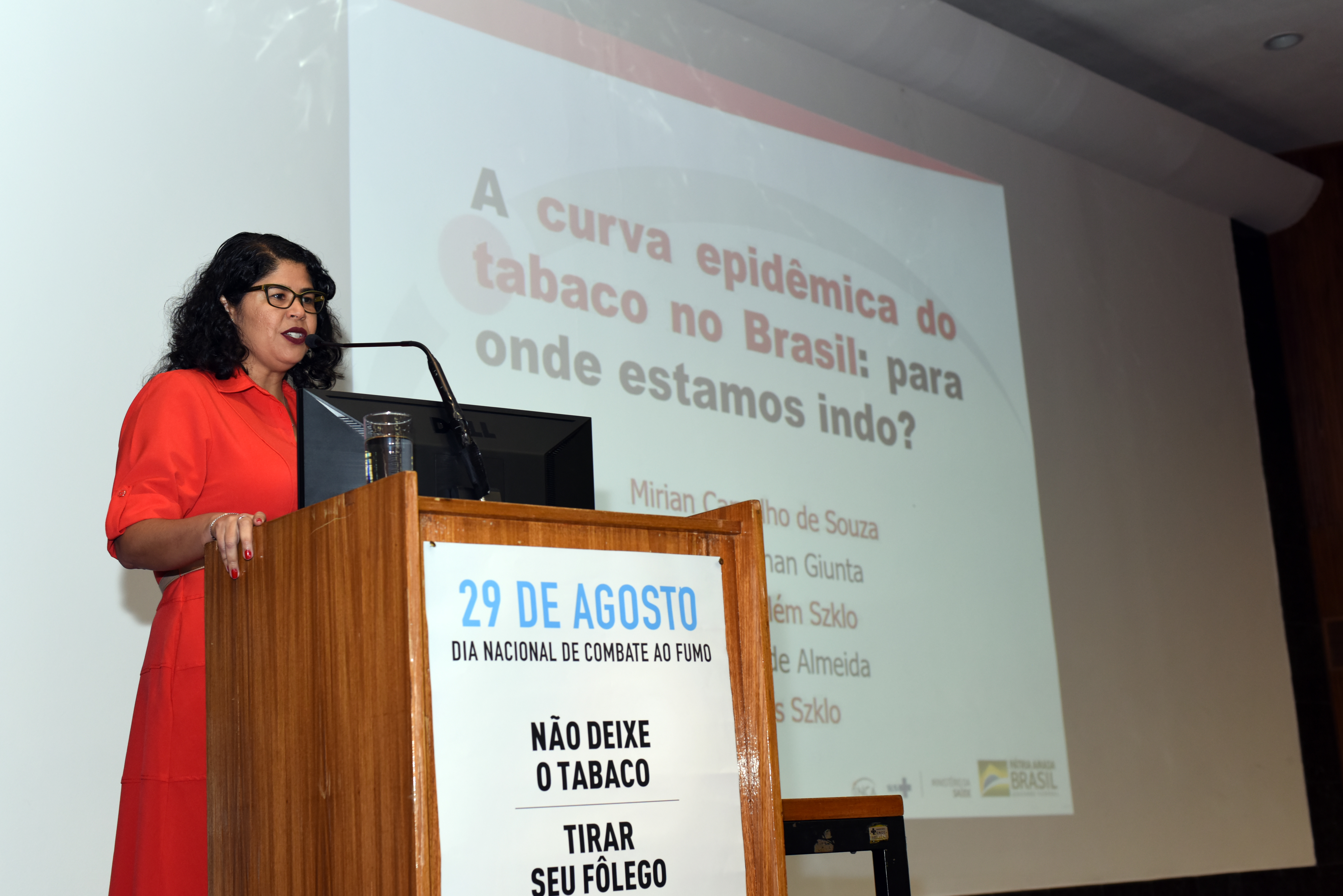 Pesquisadora Mirian Carvalho, da Divisão de Pesquisa Populacional do INCA, no palco, apresentando as conclusões do estudo sobre mortalidade no Brasil por câncer de pulmão